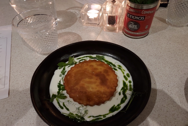 Bowl with white yogurt sauce and a round pastry in the middle. 